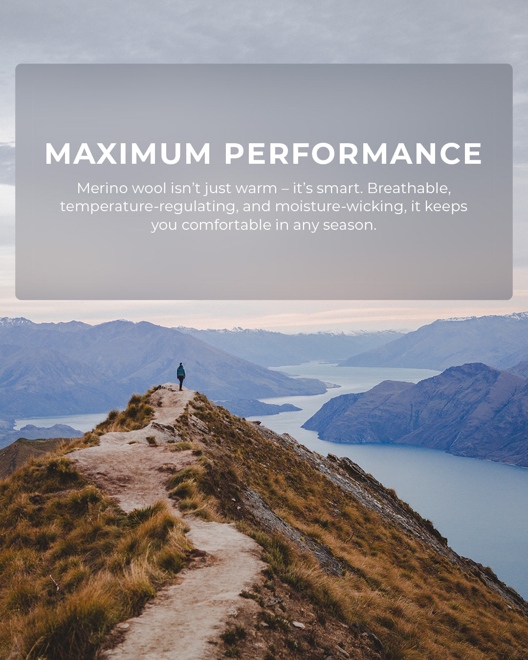Person standing on a mountain top with a scenic view, promoting merino wool's benefits.