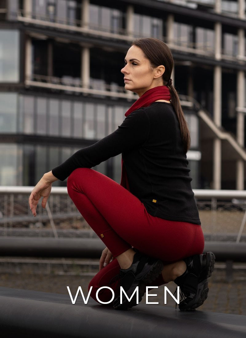 Woman in black top and red pants crouching outdoors with 'WOMEN' text overlay.
